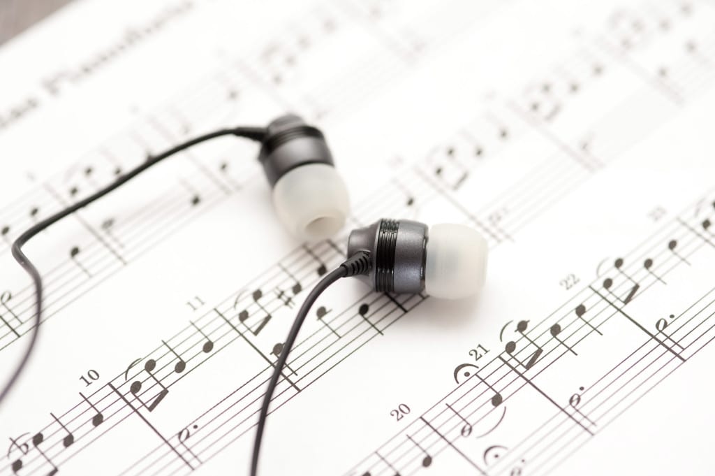 a pair of ear bud headphones on a background of sheet music notes