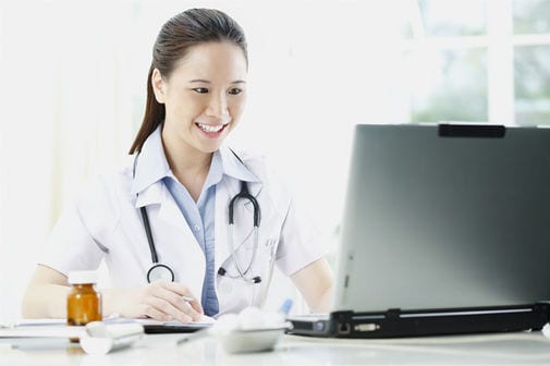 Female doctor smiling while using laptop